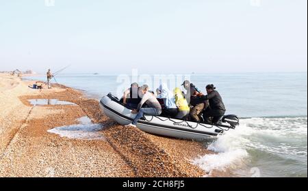 A group of people thought to be migrants arrive in an inflatable boat at Kingsdown beach, near Dover, Kent, after crossing the English Channel. Stock Photo