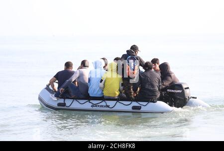 A group of people thought to be migrants arrive in an inflatable boat at Kingsdown beach, near Dover, Kent, after crossing the English Channel. Stock Photo