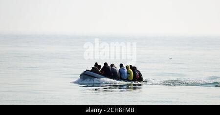 A group of people thought to be migrants arrive in an inflatable boat at Kingsdown beach, near Dover, Kent, after crossing the English Channel. Stock Photo