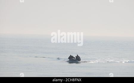 A group of people thought to be migrants arrive in an inflatable boat at Kingsdown beach, near Dover, Kent, after crossing the English Channel. Stock Photo