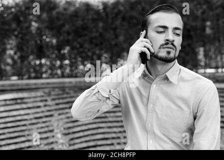 Young handsome bearded businessman talking on the phone in the city outdoors Stock Photo