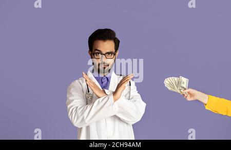 No to corruption concept. Indian medical specialist refusing bribe from patient over lilac background Stock Photo