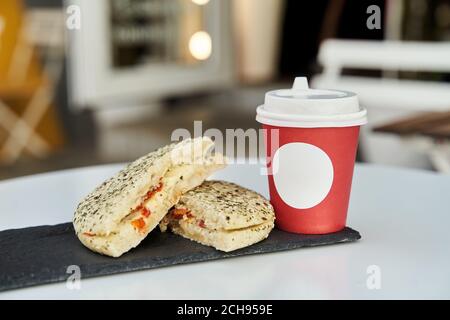 A sandwich with a red plastic glass of coffee on the table in a coffee shop. Stock Photo