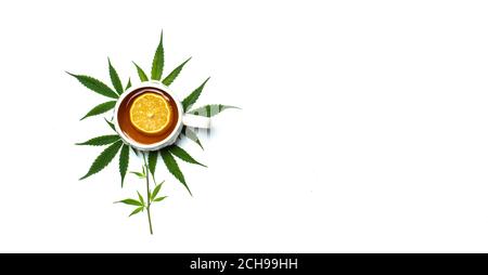 Cup of marijuana infused tea in a cup on top of marijuana leaves isolated top view with copy space Stock Photo