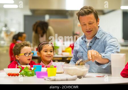 Jamie Oliver makes bread with pupils Elvis and Eleanor at Kings Cross Academy in London, during a visit on Food Revolution Day, part of the Food Revolution campaign which aims to tackle issues of child nutrition. Stock Photo