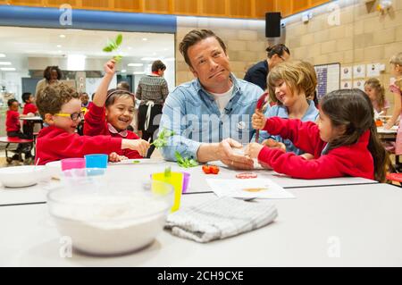 Jamie Oliver makes bread with pupils (left to right) Elvis, Eleanor, Emily and Yarden at Kings Cross Academy in London, during a visit on Food Revolution Day, part of the Food Revolution campaign which aims to tackle issues of child nutrition. Stock Photo