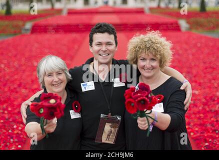 Co-creators Margaret Knight (left) and Lynn Berry with designer Philip Johnson at their 5000 Poppies exhibit - which uses almost 300,000 individually crocheted poppies, covering nearly 2,000sq m (21,000sq ft) in the grounds of the Royal Hospital Chelsea - during a preview day at the Chelsea Flower Show in London. Stock Photo