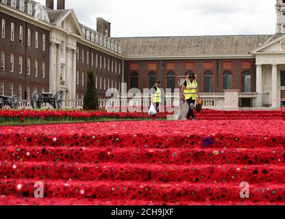 Volunteers put the finishing touches to the 5000 Poppies exhibit - which uses almost 300,000 individually crocheted poppies, covering nearly 2,000sq m (21,000sq ft) in the grounds of the Royal Hospital Chelsea - during a preview day at the Chelsea Flower Show in London. Stock Photo