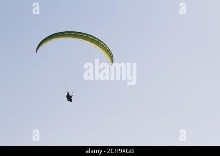 Person practicing paragliding on the cliffs of the coast. Stock Photo