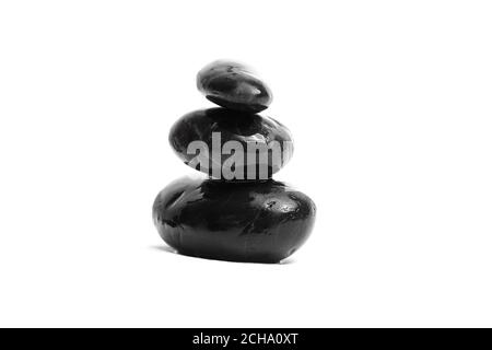 Stacked smooth black stones. Sea pebble. Balancing wet pebbles isolated on white background Stock Photo