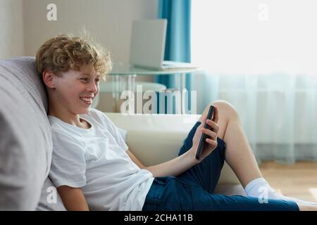 handsome teen boy talk on phone online, video translation on smartphone, look at screen. at home Stock Photo