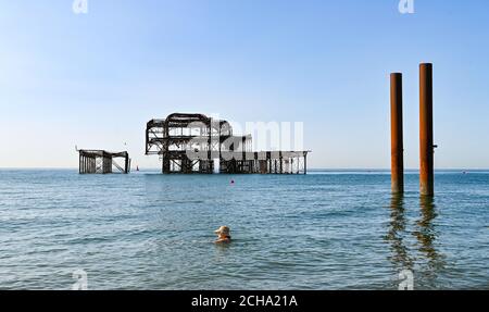 Brighton UK 14th September 2020 - A swimmer keeps her hat on as she enjoys the hot sunny weather in Brighton by the West Pier as temperatures are forecast to reach 30 degrees in parts of the South East  : Credit Simon Dack / Alamy Live News Stock Photo