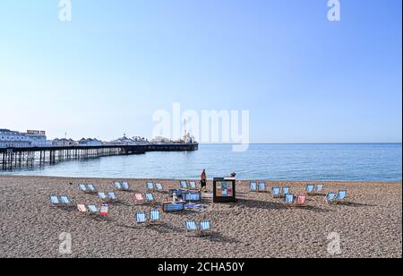 Brighton UK 14th September 2020 - A deckchair attendant lays out chairs on Brighton beach today as temperatures are forecast to reach 30 degrees in parts of the South East  : Credit Simon Dack / Alamy Live News Stock Photo