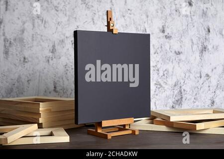 Black blank cotton canvas for acrylic and oil paints, a wooden easel and stretcher bars on table Stock Photo
