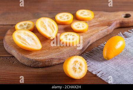 sliced kumquats on a wooden kitchen board, close up, selective focus. Stock Photo