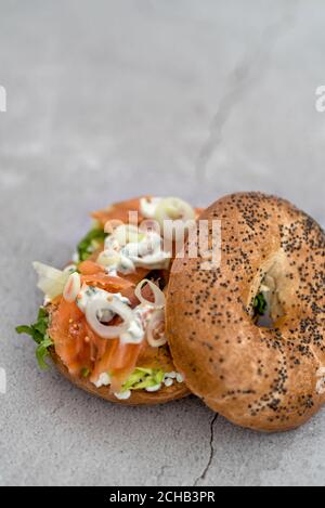 Salmon bagel with cream cheese, fresh herbs and veggies on a marble counter Stock Photo