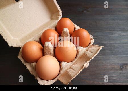 Six of Organic Chicken Eggs in Paper Carton Box Isolated on Dark Color Wooden Background Stock Photo