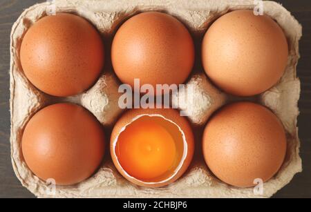 Pack of fresh organic eggs with an opened shell one in the carton box Stock Photo
