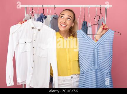 Young woman holding hangers with dress and shirt Stock Photo