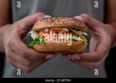 Woman holding a lox bagel with cream cheese and veggies Stock Photo