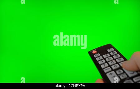 Male hand with remote control pointing on TV screen. Green chroma key. Stock Photo