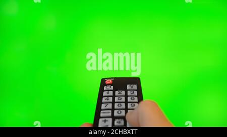 Male hand with remote control pointing on TV screen. Green chroma key. Stock Photo