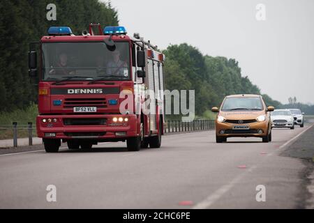 EMBARGOED TO 0001 THURSDAY JUNE 22 EDITORIAL USE ONLY A West Midlands Fire Service engine overtakes a line of connected cars equipped with research technology that alerts the driver when an emergency vehicle is approaching as well as the direction it is travelling in, during a media demonstration at the HORIBA MIRA proving ground in Nuneaton, Warwickshire. Stock Photo