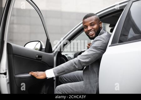 Black man in suit getting in car Stock Photo