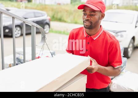 young african black man work in delivery company, came to clients to give it, wearing red uniform Stock Photo