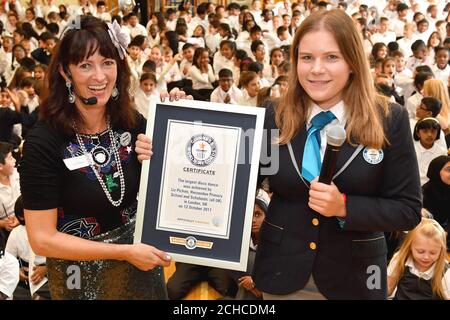 EDITORIAL USE ONLY Author Liz Pichon (left) collects the record from Adjudicator Paulina Sapinska as 314 pupils from Horsenden Primary School in Middlesex break a Guinness World Records title for largest disco dance, which had previously been 280, to celebrate the launch of Liz's new book Tom Gates:Epic Adventure (Kind of!) published by Scholastic UK.  Stock Photo