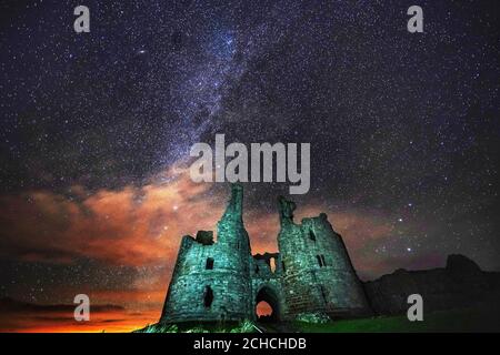 The great gatehouse of Dunstanburgh Castle ruins in Alnwick, Northumberland, under a starry sky. Stock Photo