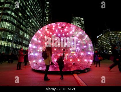 Members of the public view Sonic Bubble by Eness at the annual Canary Wharf Winter Lights festival 2018, London.