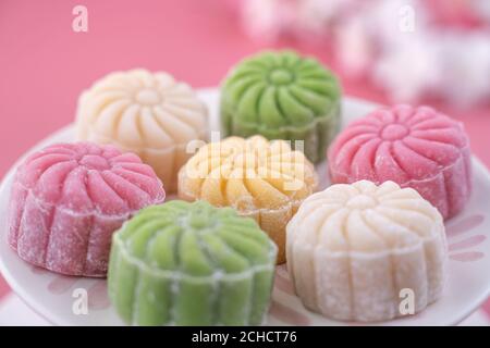 Colorful snow skin moon cake, sweet snowy mooncake, traditional savory dessert for Mid-Autumn Festival on pastel pale pink background, close up, lifes Stock Photo