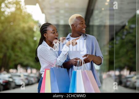 Surprised african american guy and girl saw original thing in shop window Stock Photo