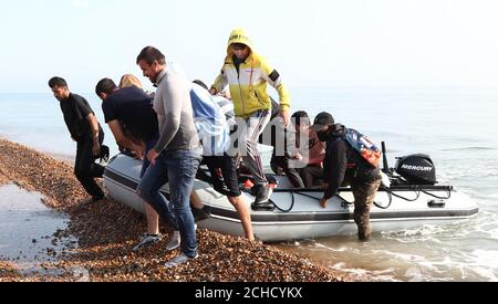 A group of people thought to be migrants arrive in an inflatable boat at Kingsdown beach, near Dover, Kent, after crossing the English Channel. Stock Photo