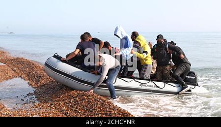 A group of people thought to be migrants arrive in an inflatable boat at Kingsdown beach, near Dover, Kent, after crossing the English Channel. Stock Photo