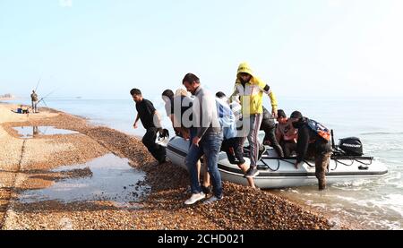 A group of people thought to be migrants arrive in an inflatable boat at Kingsdown beach, near Dover, Kent, after crossing the English Channel. Stock Photo