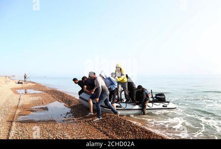 A group of people thought to be migrants arrive in an inflatable boat at Kingsdown beach, near Dover, Kent, after crossing the English Channel. Stock Photo