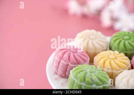 Colorful snow skin moon cake, sweet snowy mooncake, traditional savory dessert for Mid-Autumn Festival on pastel pale pink background, close up, lifes Stock Photo