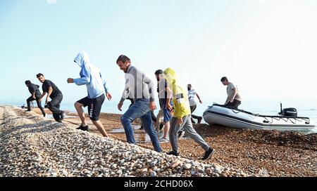 A group of people thought to be migrants arrive in an inflatable boat at Kingsdown beach, near Dover, Kent, after crossing the English Channel. Stock Photo