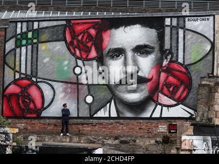 Artist Bobby McNamara known as Rogue-one views his latest work, a giant street art mural dedicated to Charles Rennie Mackintosh painted on a large wall overlooking the Clutha bar in Glasgow. Stock Photo