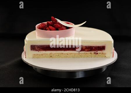 Half or slice of white chocolate mousse and strawberries cake isolated on black background. Copy space. High quality photo.  Stock Photo