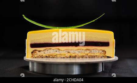 Half or slice of mango mousse glazed cake isolated on black background. Copy space. High quality photo.  Stock Photo