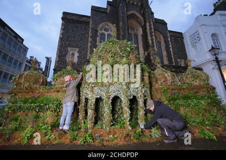 Plant expert,Tomoko O'Reilly (left) and Iain Prendergast put the finishing touches to a 12ft tall replica of the Brighton Pavilion made from plants, created by Seventh Generation and Plantlife on display in Brighton to encourage people to sign an online petition calling on Government to invest more in plant-based solutions to combat climate change. Stock Photo