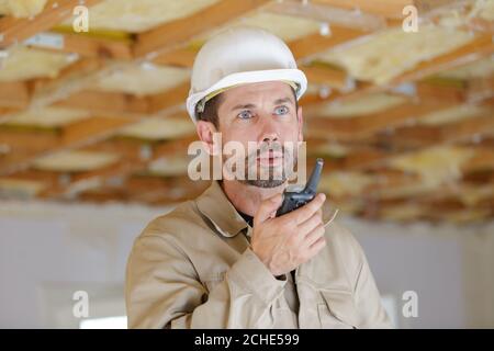 male builder indoors using walkie talkie Stock Photo