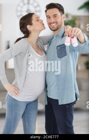 picture showing happy couple kissing while holding baby shoes Stock Photo