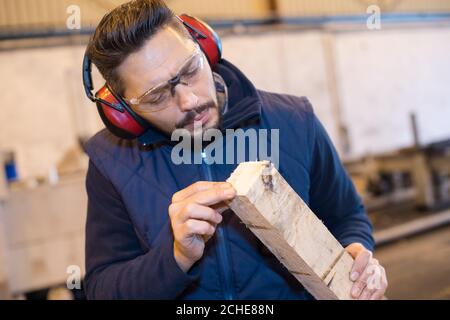 carpenter checking wood plank evenness at workshop Stock Photo