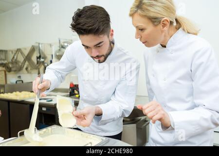 female and male chef making white chocolate Stock Photo