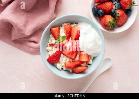 Cottage cheese, tvorog with fresh strawberries and yogurt in bowl on pink background, top view. Healthy breakfast or snack food. Source of protein and Stock Photo