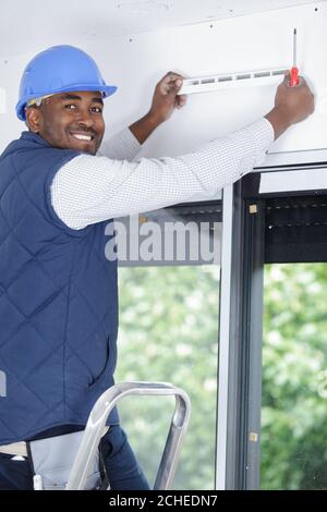 contractor installing ventillation grill above patio doors Stock Photo